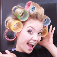Cheerful funny blond girl hair curlers by haidresser in salon