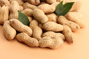 tasty peanuts with green leaves, on beige background
