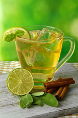 Transparent cup of ice green tea on table on bright background