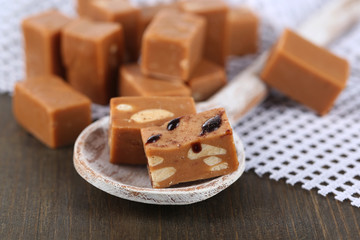 Many toffee in wooden spoon on napkin on wooden table