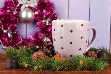 Cup of hot cacao with chocolates and fir branches