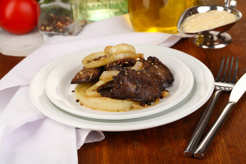 Fried chicken livers on plate on wooden table close-up