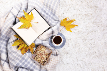 Composition with warm plaid, book, cup of hot drink