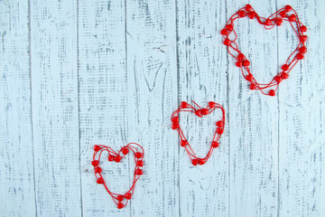 Heart-shaped beads on string on wooden background