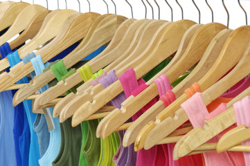 Colorful summer t-shirts hanging on wooden hangers