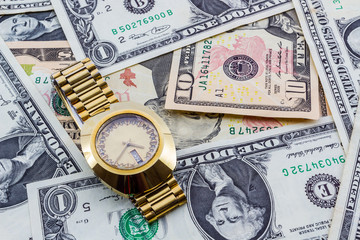 Wristwatch on a heap of paper dollars.