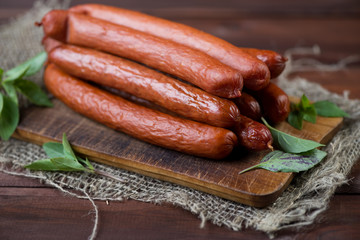 Smoked sausages on a rustic wooden chopping board, close-up