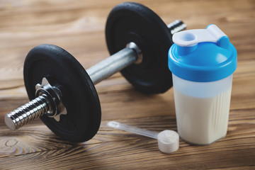 Protein shake with a dumbbell and a measuring scoop