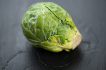 Fototapeta premium Fresh brussels sprout over black wooden background