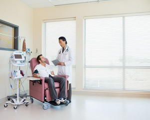 Doctor With Digital Tablet Discussing With Patient In Chemo Room