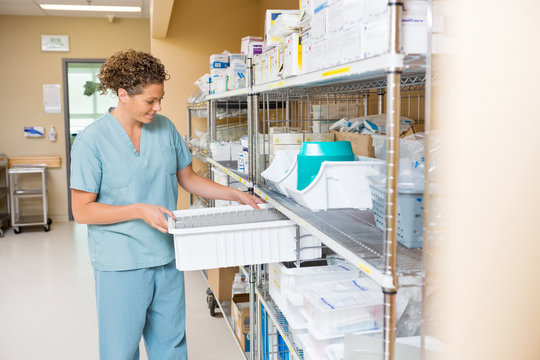 Nurse Arranging Container On Shelf In Storage Room