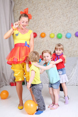Four kids and entertainer play game at funny children party.