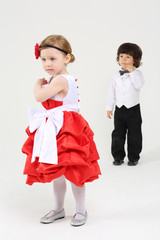 Little pretty girl in beautiful dress stands and boy stands