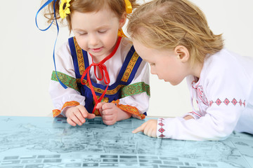 Little boy and girl in Russian folk costumes look at map