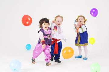 Fototapeta premium Little girl and two boys in folk costumes play with balloons