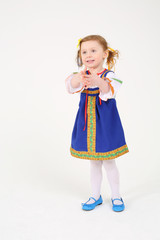 Little girl in russian folk costume stands and smiles on white