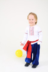 Little boy in russian folk costume stands and smiles on white