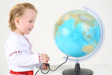 Fototapeta premium Little boy in russian folk costume looks at big world globe