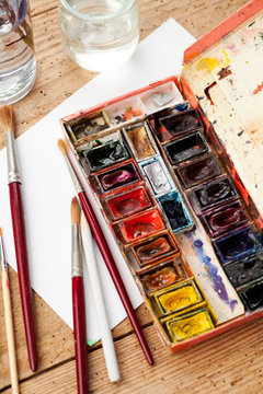 Watercolor paint box and brushes for painting .