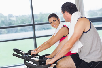 Fototapeta na wymiar Young woman and man working out at spinning class