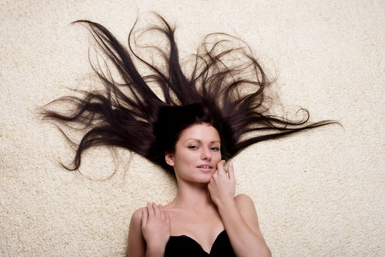 Portrait of a woman with long brown hair lying on the floor