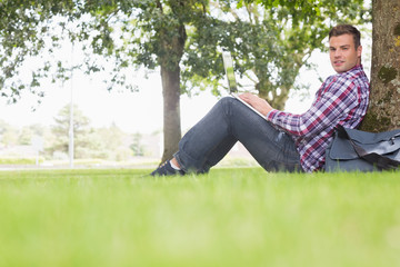 Obraz premium Happy student using his laptop to study outside