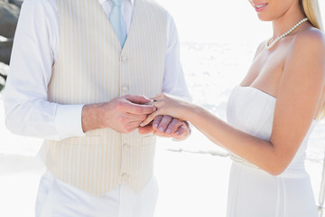 Fototapeta na wymiar Man placing ring on smiling brides finger