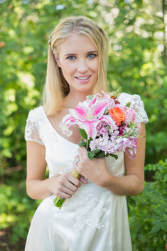 Blonde smiling bride holding bouquet looking at camera