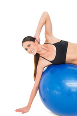 Fototapeta premium Side view of a fit woman stretching on fitness ball
