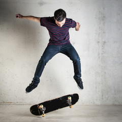 Skateboarder jumping against concrete wall.