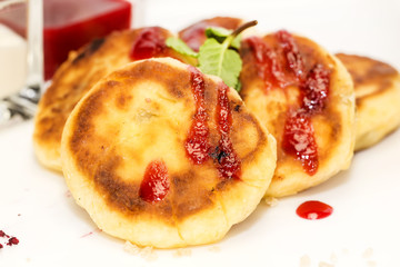 cheesecakes with sour cream and jam on table in restaurant