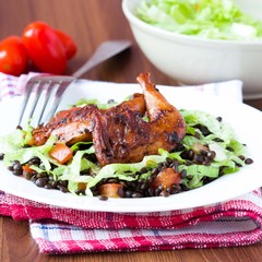 Delicious salad with black lentils, fried legs quail, tomatoes