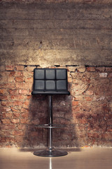 Modern chair against a grungy brick wall
