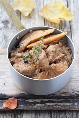 Portion of meat goulash with quince on a rustic background.