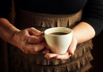 Hands of senior woman holding cup of coffee