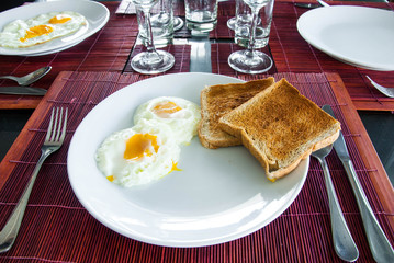 eggs and toasts on white plate on dining table