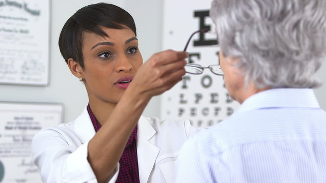 African American optometrist gives eyeglasses to senior woman