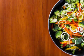 frying vegetables in pan with wood background