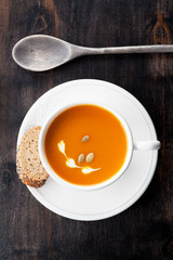 Pumpkin soup with pumpkin seeds on a wooden background