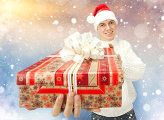 Young man in Santa Claus hat holding a gift box