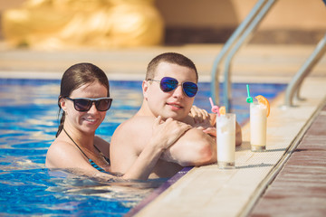 Beautiful couple drinking cocktails, hugging and kissing in the 