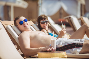 Beautiful couple drinking cocktails, hugging and kissing in the 