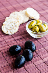 Black and green olives with rice cakes on bamboo napkin