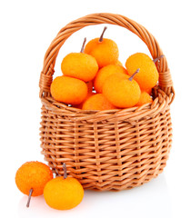 Small tangerines in wicker basket, isolated on white