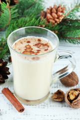 Cup of eggnog with fir branches on wooden background