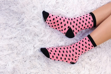 Female legs in colorful socks on white carpet background