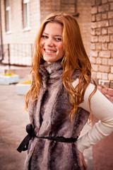 Outdoor portrait of cute redhead girl smiling on street