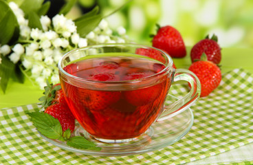 Delicious strawberry tea on table on bright background