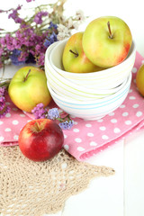 Juicy apples on plate on white wooden table