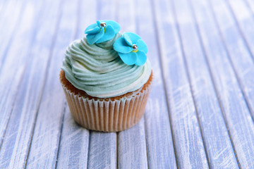 Tasty cupcake with butter cream, on color wooden background